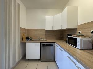 a kitchen with white cabinets and a sink and a microwave at The Central's Pearl - Centre - 6p - Rêve au Mans in Le Mans