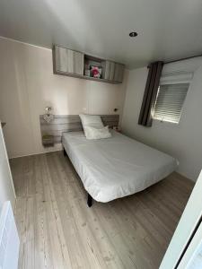 a bedroom with a white bed and a wooden floor at Mobil Home 2CH Bien Equipé Valras-Plage in Sérignan