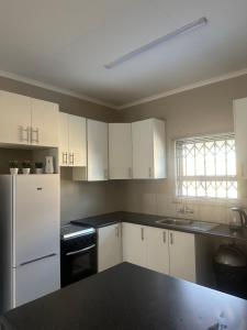 a kitchen with white cabinets and a white refrigerator at NO LOADSHEDDING Two Bedroom Unit in Trichardt