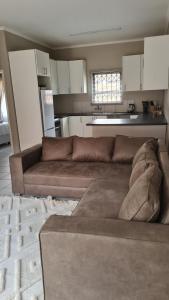 a living room with a brown couch and a kitchen at NO LOADSHEDDING Two Bedroom Unit in Trichardt