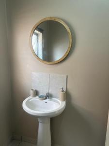 La salle de bains est pourvue d'un lavabo blanc et d'un miroir. dans l'établissement NO LOADSHEDDING Two Bedroom Unit, à Trichardt