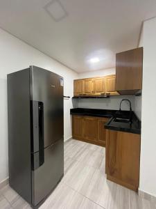 a kitchen with a stainless steel refrigerator and wooden cabinets at Hotel Backdoor in Imbituba