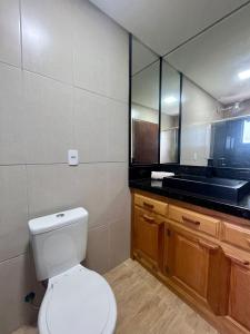 uma casa de banho com um WC branco e um espelho. em Hotel Backdoor em Imbituba