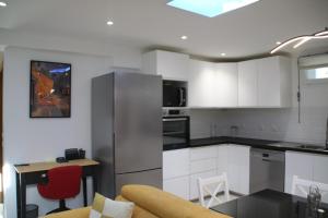 a kitchen with white cabinets and a couch and a table at Appartement moderne & chaleureux près de La Défense in Argenteuil