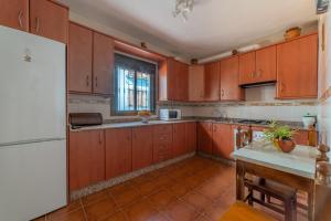 cocina con armarios de madera y nevera blanca en la casa del bosque, en Júzcar