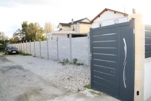 a fence with a black gate in front of a driveway at maison canoa in Argenteuil