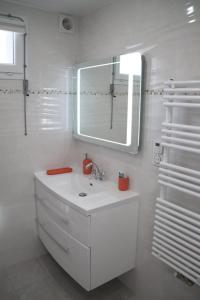 a white bathroom with a sink and a mirror at maison canoa in Argenteuil