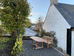 a wooden table and bench next to a building at Butterfly Cottage in Grantown on Spey