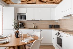 a kitchen with a wooden table and white cabinets at Kingwest Villa - free parking, sauna & 5 bedrooms in Tampere