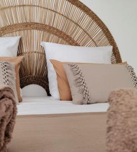 a bed with white pillows and a wicker headboard at Bohême Carib - Massage offert à partir de 3 nuits in Deshaies