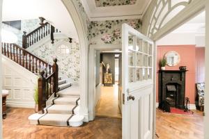 a hallway with a staircase in a home with floral wallpaper at Hillthorpe Manor by Maison Parfaite - Large Country House with Hot Tub in Pontefract