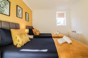 1 dormitorio con 2 camas y paredes amarillas en FREE Parking, 1 bedroom apartment close to HEATHROW en Stanwell
