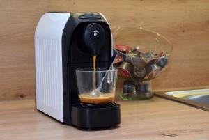 a coffee maker is pouring coffee into a glass at M10 Apartman in Pécs