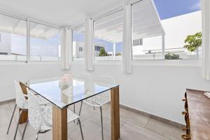 a dining room with a glass table and white chairs at Villa Atlántica - Heated pool in Playa Blanca in Playa Blanca