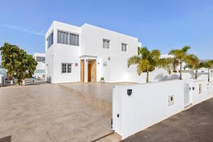 a white house with palm trees in front of it at Villa Atlántica - Heated pool in Playa Blanca in Playa Blanca