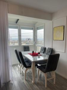 una sala da pranzo con tavolo, sedie e finestre di Dielli Apartment New a Pristina Altre 6 foto
