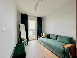 a living room with a green couch and a window at River Paradise with Parking Spot in Wrocław