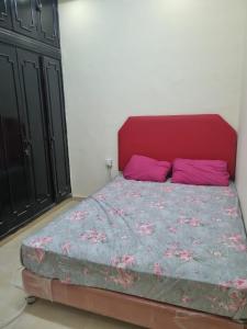 a bedroom with a bed with a red headboard and pink pillows at Budget Hostel Rooms in Al Ain