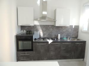 a kitchen with white cabinets and a sink and a stove at Casa Cortina in Domodossola