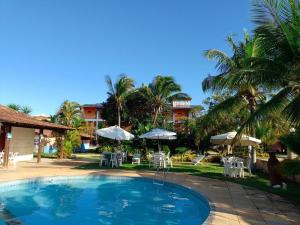 una piscina in un resort con tavoli e ombrelloni di Pousada Cheiro de Mar a Nova Viçosa