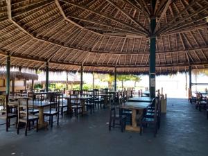 a restaurant with tables and chairs and a straw roof at Pousada Cheiro de Mar in Nova Viçosa