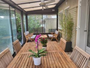 un patio al aire libre con mesas de madera, sillas y flores en Maison à louer 3 chambres en Sartrouville