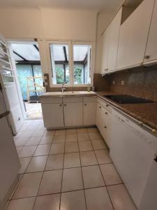 een keuken met witte kasten en een tegelvloer bij Maison à louer 3 chambres in Sartrouville