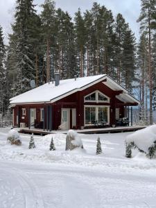 una pequeña casa en la nieve con árboles delante en Holiday Home Amero purnu 4 en Kolinkylä