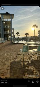 a patio with two chairs and a building with palm trees at Coastal Waters 209 in New Smyrna Beach