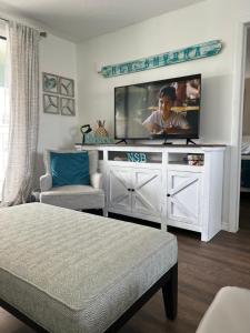 a living room with a flat screen tv on a entertainment center at Coastal Waters 209 in New Smyrna Beach