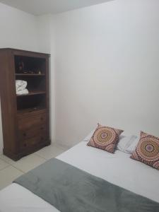a bed with two pillows and a cabinet in a room at Condomínio mais Maracanã BL 1 AP 111 in Rio de Janeiro