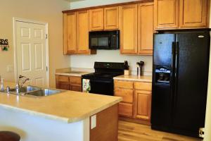 a kitchen with a black refrigerator and wooden cabinets at Luxurious Condo at the Springs by Cool Properties in Mesquite