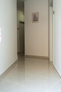 einen Flur mit weißen Wänden, weißen Böden und einer Tür in der Unterkunft Anesis Airport rooms 102 in Koropi