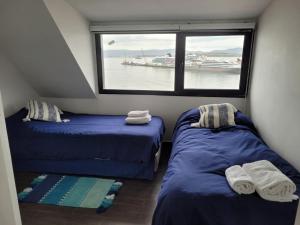 two beds in a small room with a window at Amaneciendo frente al Beagle in Ushuaia