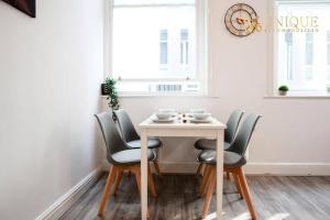 a dining room table with chairs and a white table at Luxury 2-bed Haven in Liverpool in Liverpool