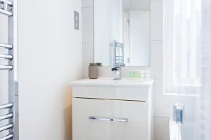 a white bathroom with a sink and a mirror at Stylish 1 Bedroom Apartment in Central London in London