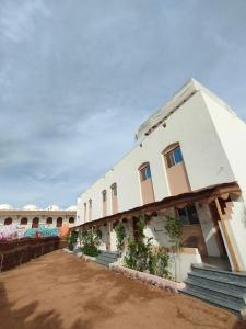 a large white building with plants in the courtyard at Al Deira Dahab Hotel in Dahab