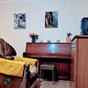 ein Wohnzimmer mit einem Klavier und einem Stuhl in der Unterkunft cozy and warm in Tbilisi City