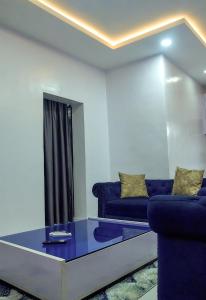 ein Wohnzimmer mit blauen Sofas und einem Glastisch in der Unterkunft JKA1-Bedroom Luxury Serviced Apartment in Lagos