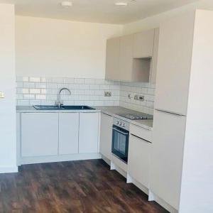 una cocina blanca con armarios blancos y fregadero en Centrally Located 3 Bed Apartment, en Cardiff
