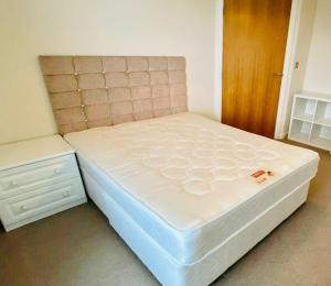 uma cama branca num quarto com uma porta de madeira em Centrally Located 3 Bed Apartment em Cardiff
