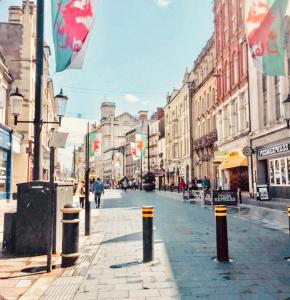 a street in a city with people walking down the street at Centrally Located 3 Bed Apartment in Cardiff
