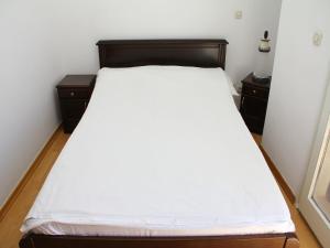 a bedroom with a bed with white sheets and two night stands at Holiday Home Blaž in Primošten
