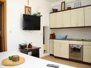 a kitchen with white cabinets and a tv on the wall at Holiday Home Blaž in Primošten
