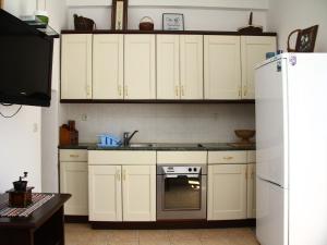 a kitchen with white cabinets and a white refrigerator at Holiday Home Blaž in Primošten +4 photos