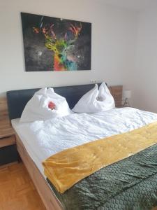 a bed with white sheets and a painting on the wall at Appartement Gamlitz in Gamlitz