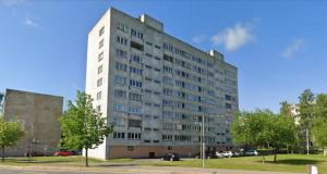 a tall white building with cars parked in a parking lot at Hero Avenue Apartment in Narva