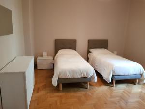 twee bedden in een kamer met houten vloeren bij Dimora Mafalda in LʼAquila