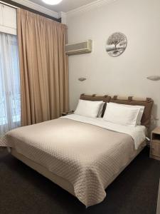 - une chambre avec un lit doté de draps blancs et une fenêtre dans l'établissement Mets, à Athènes
