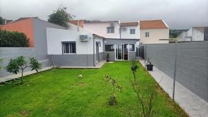 a backyard of a house with a green yard at Casa das Capelas - Perfect for families in Ponta Delgada
